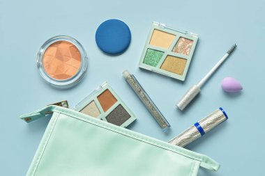 Mavi arka planda farklı dekoratif kozmetik ürünlere sahip çanta