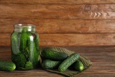 Ahşap arka planda konserve konserveler için taze salatalıklı kavanoz.