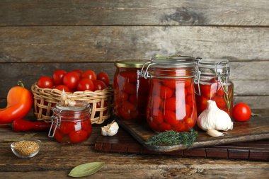 Kavanozlar dolusu domates turşusu ve ahşap arka planda farklı baharatlar.