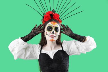 Yeşil arka planda Cadılar Bayramı için giyinmiş güzel bir kadın.