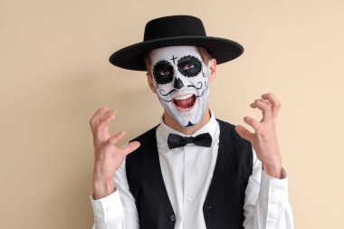 Cadılar Bayramı için bej arka planda giyinmiş korkutucu genç adam.