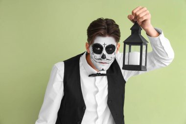 Cadılar Bayramı için giyinmiş yeşil arka planda feneri olan genç adam.