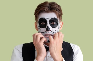 Cadılar Bayramı için giyinmiş korkmuş genç adam yeşil arka planda, yakın plan