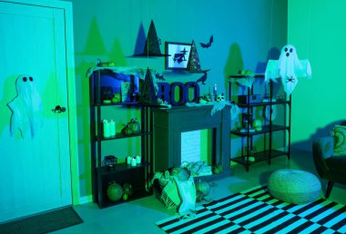 Cadılar Bayramı için kapı ve şömine raflarıyla dekore edilmiş karanlık oturma odasının içi.