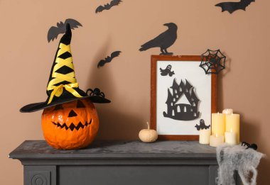 Cadılar Bayramı dekorlu şömine rafı ve odada yanan mumlar.