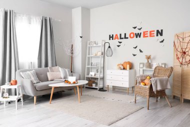 Cadılar Bayramı için dekore edilmiş oturma odasının içi kanepe ve koltukla dolu.