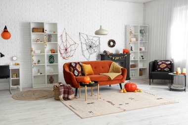 Cadılar Bayramı için kanepe ve balkabaklarıyla dekore edilmiş aydınlık oturma odasının içi.