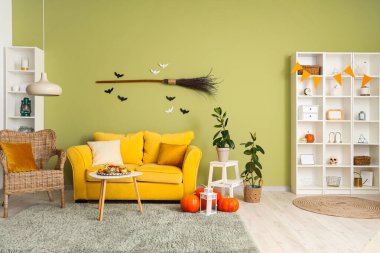 Cadılar Bayramı için sarı kanepe ve raf ünitesiyle dekore edilmiş oturma odasının içi.