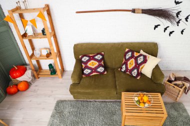 Cadılar Bayramı için yeşil kanepe ve cadı süpürgesiyle dekore edilmiş oturma odasının içi.