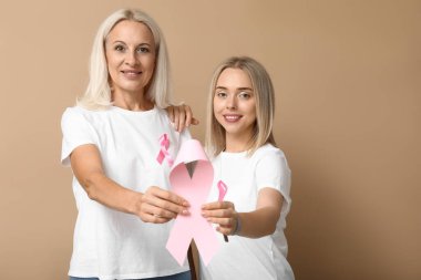 Women with pink ribbon on beige background. Breast cancer awareness concept clipart