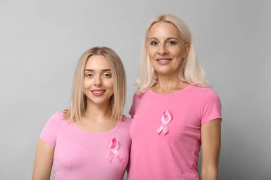 Gri arka planda pembe kurdeleli kadınlar. Göğüs kanseri farkındalığı konsepti