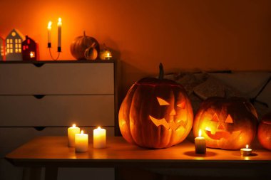 Cadılar Bayramı balkabakları ve karanlık oturma odasında yanan mumlar.