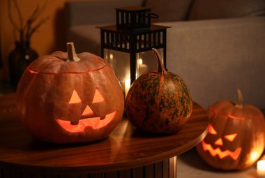 Karanlık oturma odasındaki masada yanan mumlarla Cadılar Bayramı balkabakları, yakın plan