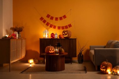 Cadılar Bayramı balkabakları ve yanan mumlarla dolu karanlık oturma odasının içinde.