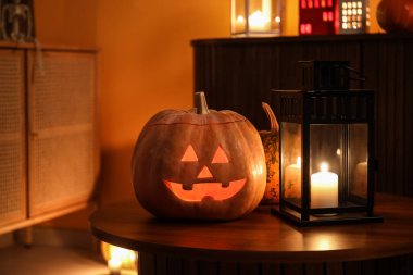 Karanlık oturma odasındaki masada yanan mumlarla Cadılar Bayramı balkabakları, yakın plan