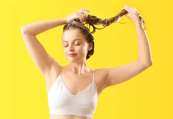 stock image Young woman washing hair on yellow background