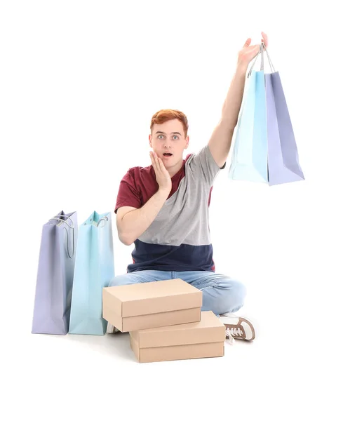 Schockierter Junger Rothaariger Mann Mit Einkaufstüten Und Schachteln Auf Weißem — Stockfoto