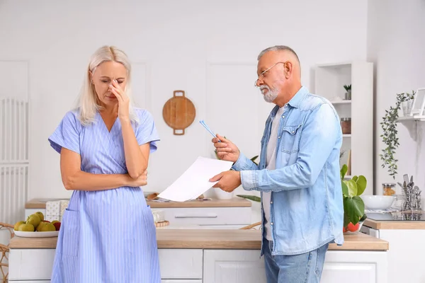 Upset mature couple with divorce decree in kitchen