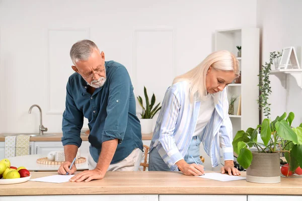 Mature couple signing divorce decree in kitchen