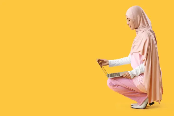 Mujer Musulmana Joven Con Portátil Sentado Sobre Fondo Amarillo —  Fotos de Stock