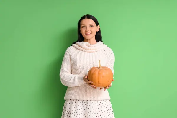 Beautiful woman with pumpkin on green background
