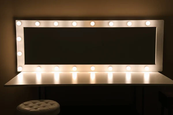 Dressing table with glowing mirror in dark makeup room