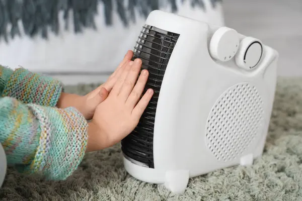 可爱的小女孩在家里电风扇加热器旁暖手 — 图库照片