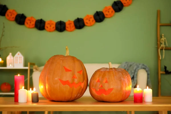 Halloween pumpkins with burning candles on table in living room