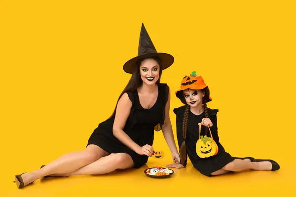 Dziewczynka Jej Matka Ubrana Halloween Smakołykami Żółtym Tle — Zdjęcie stockowe
