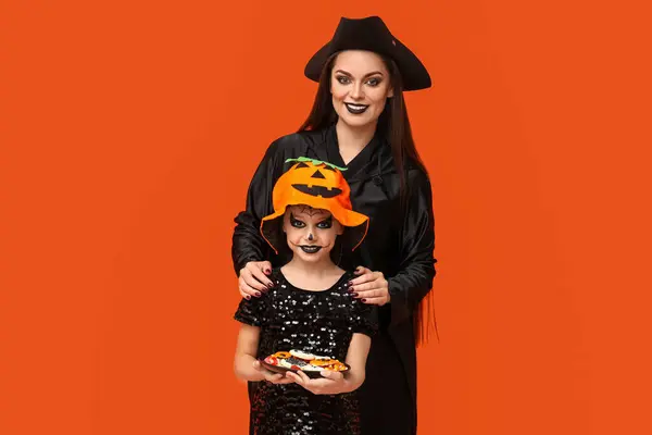 Κοριτσάκι Κεράσματα Και Μητέρα Της Ντυμένη Για Halloween Πορτοκαλί Φόντο — Φωτογραφία Αρχείου