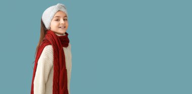 Mavi arka planda kışlık giysiler içinde şirin küçük bir kız. Mesaj için yeri var.