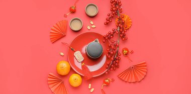 Kırmızı zemin üzerinde çaydanlık, fincan, mandalina ve Çin sembolleri olan tabaklar, üst görünüm