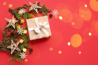 Noel hediyesi, köknar dalları ve kırmızı arkaplanda metin için boşluk olan dekor