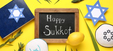 Dört tür (lulav, hadas, arava, etrog), torah ve sarı arkaplanda Mutlu SUKKOT yazılı karatahta