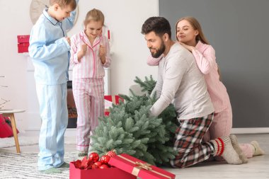 Mutlu ebeveynler ve evde Noel ağacı olan küçük çocukları.