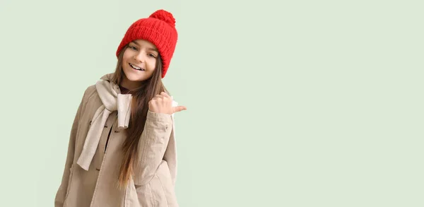冬の服でかわいい女の子は テキストのためのスペースを持つ軽い背景に何かを指摘する — ストック写真