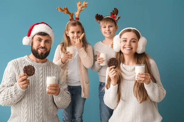 Happy family with Christmas cookies and glasses of milk on blue background