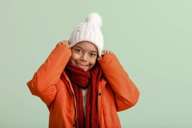 Hafif arka planda sıcak kış kıyafetleri içinde sevimli Afro-Amerikalı çocuk.