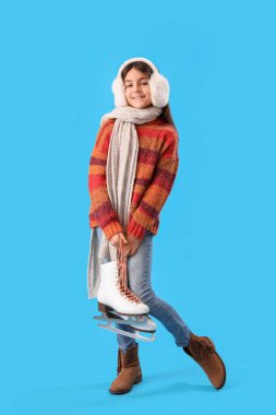 Mavi arka planda buz patenleriyle kışlık giysiler içinde şirin küçük bir kız.