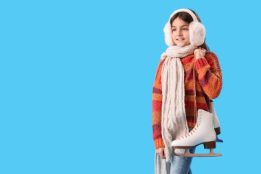 Mavi arka planda buz patenleriyle kışlık giysiler içinde şirin küçük bir kız.