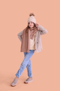 Bej arka planda kışlık giysiler içinde şirin küçük bir kız.