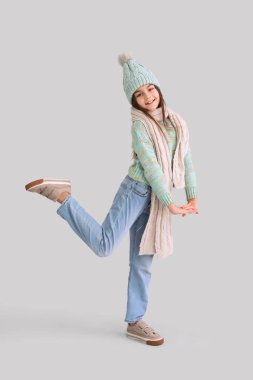 Leylak arka planında kışlık giysiler içinde şirin küçük bir kız.