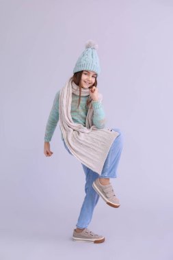 Kış giysileri içinde, leylak arka planda mutlu küçük kız.