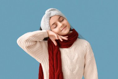 Mavi arka planda kışlık giysiler içinde şirin küçük bir kız.