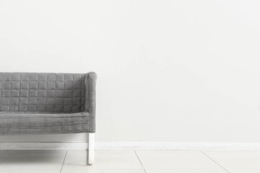 Stylish grey sofa near white wall