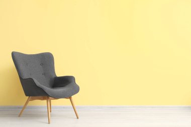 Sarı duvarın yanındaki modern gri koltuk