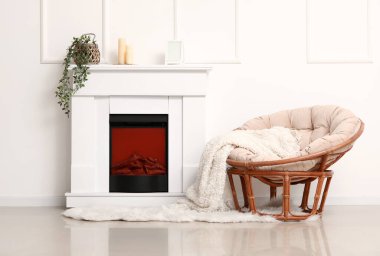 Beyaz duvarın yanında battaniyeli ve şömineli rahat bir koltuk.