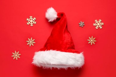 Kırmızı arka planda kar taneleri olan Noel Baba şapkası