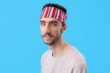 Mavi arka planda şık başörtüsü olan esmer genç adam, yakın plan.