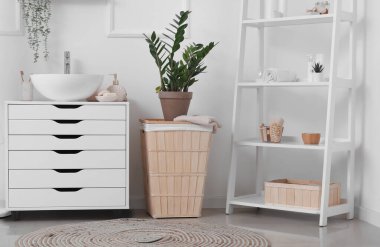 Banyo aksesuarlı lavabo, çekmeceler, saksı ve banyodaki raf ünitesi.